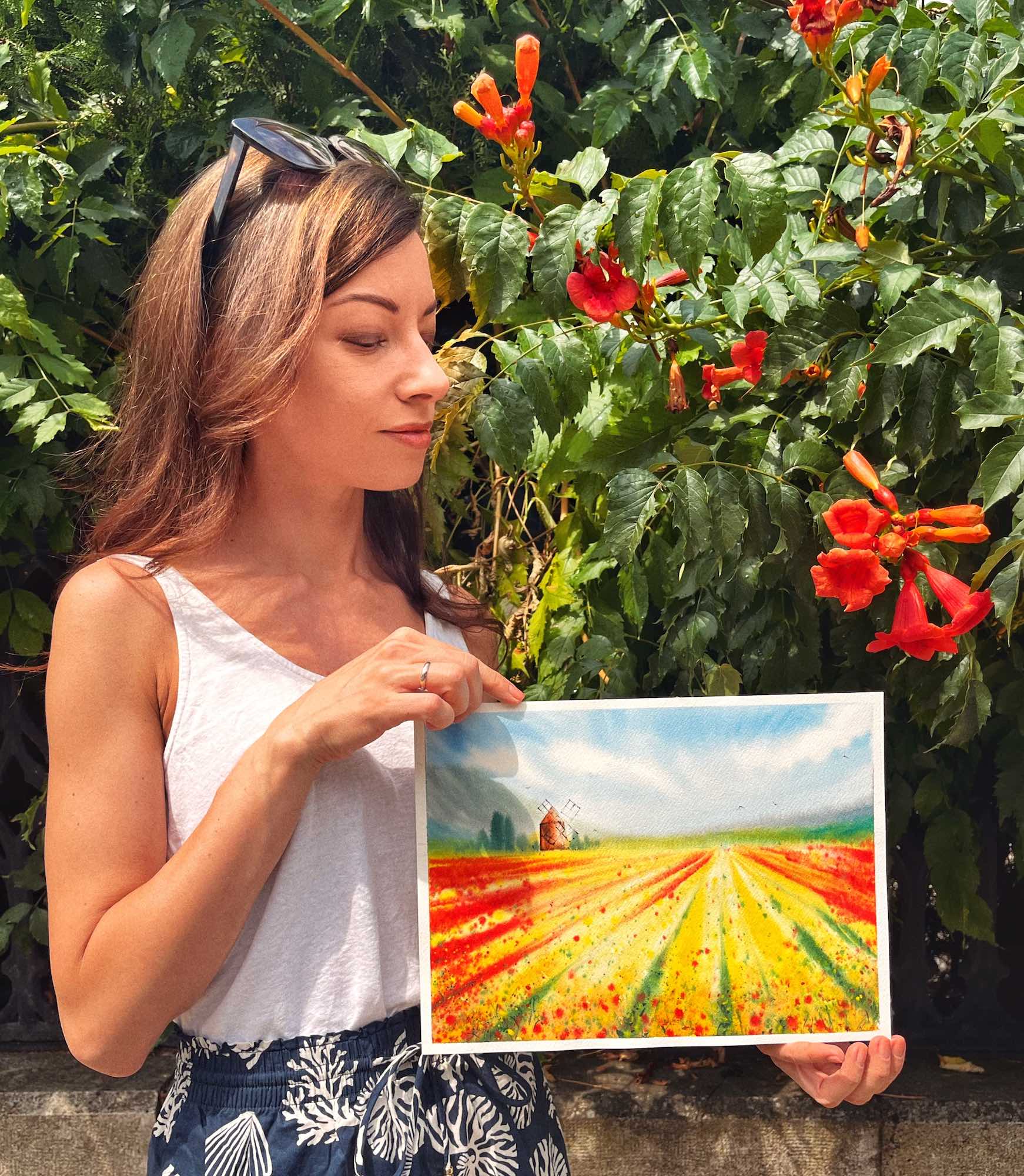 Elina holding a vibrant watercolor landscape