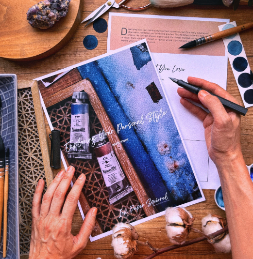 A flatlay: watercolor workbook, brushes, paint swatches
