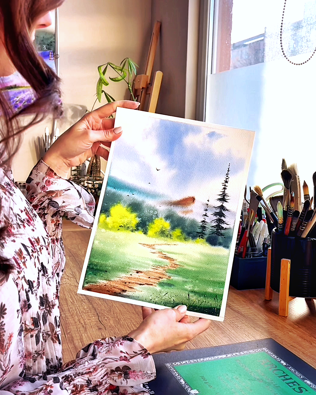 Elina in her studio showing a finished watercolor piece
