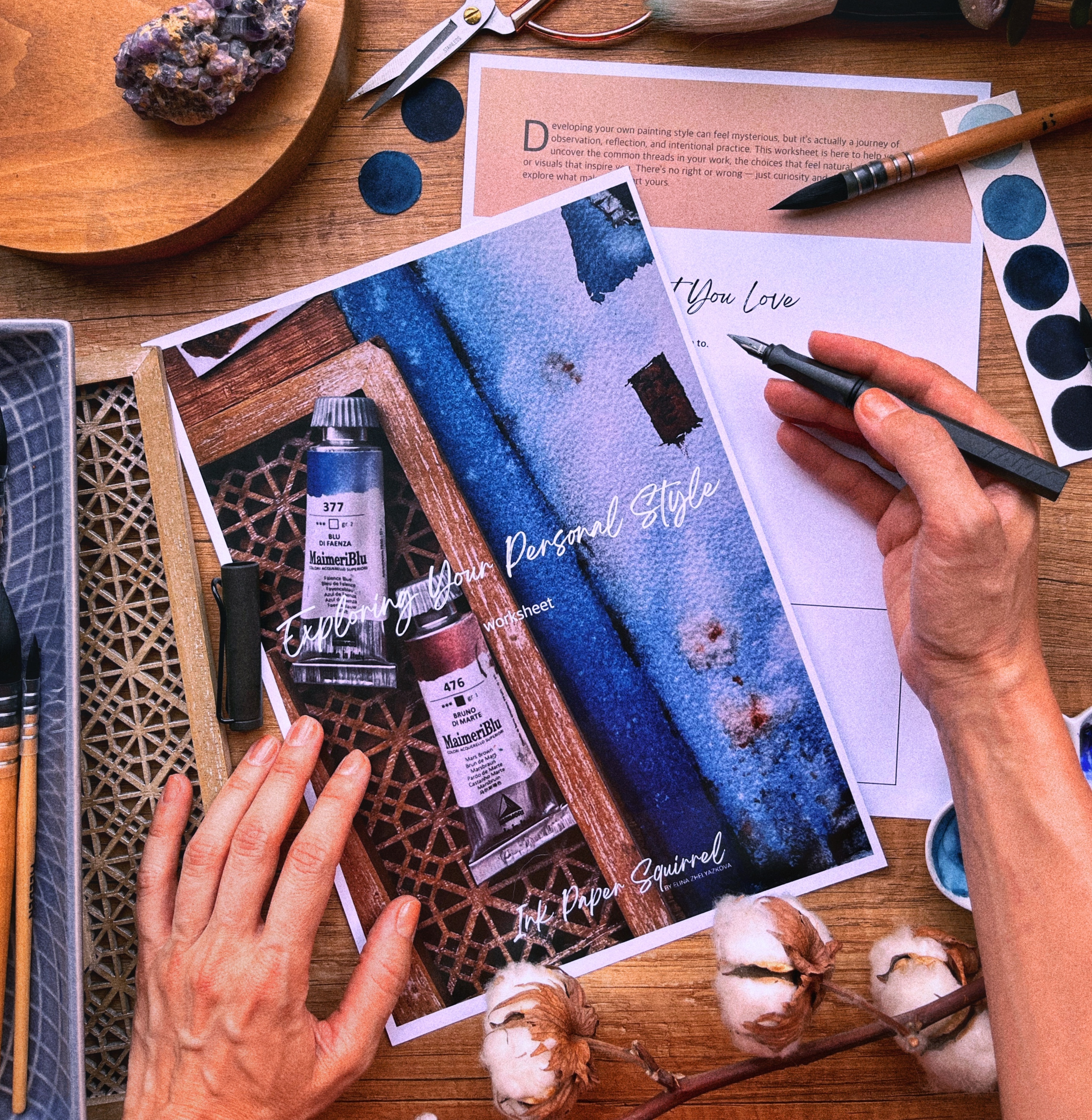 A flatlay: watercolor workbook, brushes, paint swatches