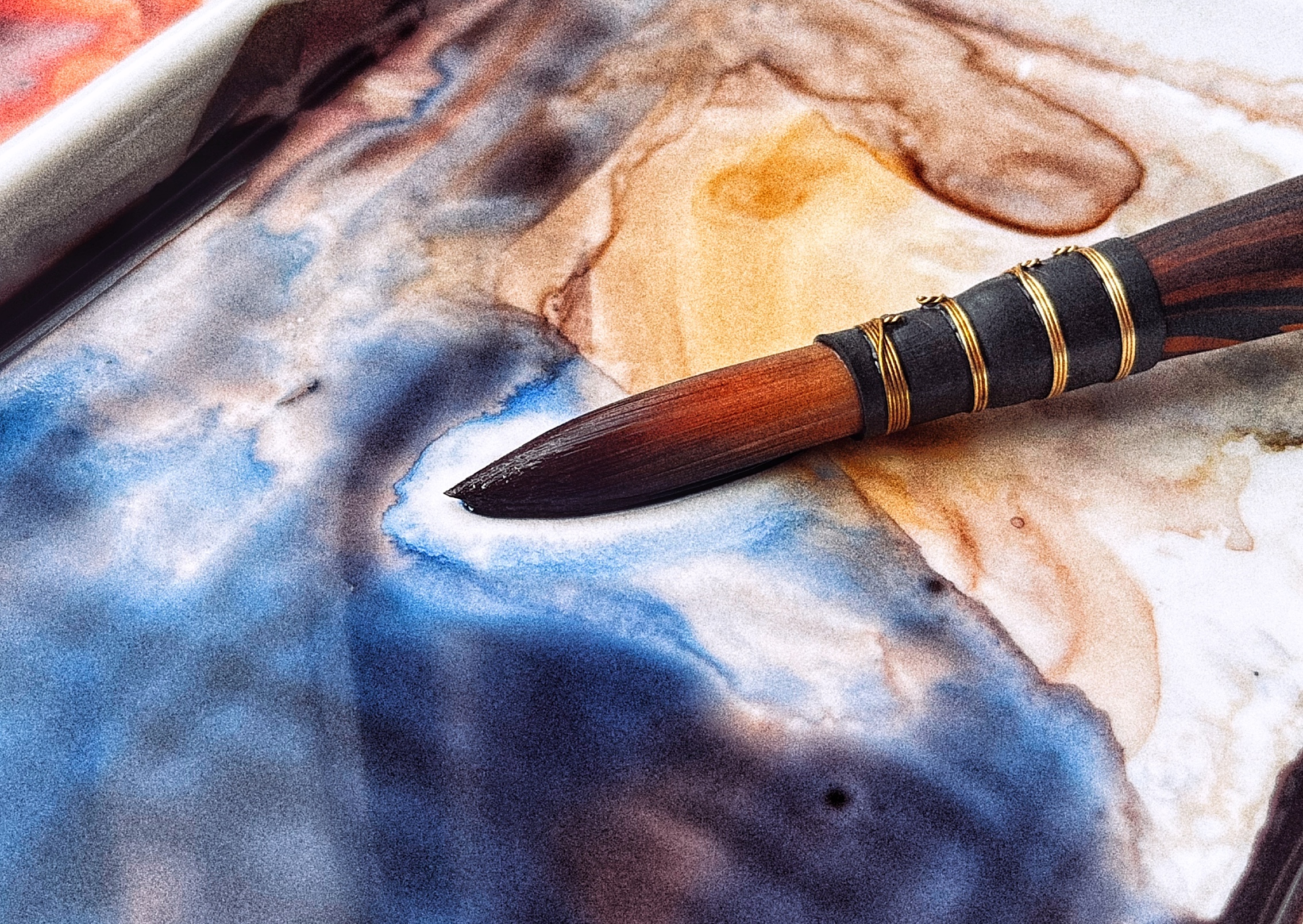 A watercolor brush resting on a palette